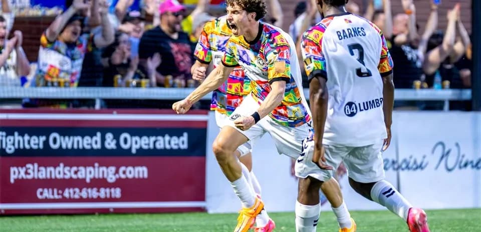 Jugador celebra un gol con aficionados de fondo