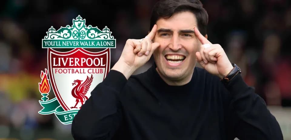 Entrenador señalando mientras sonríe junto al logo de Liverpool