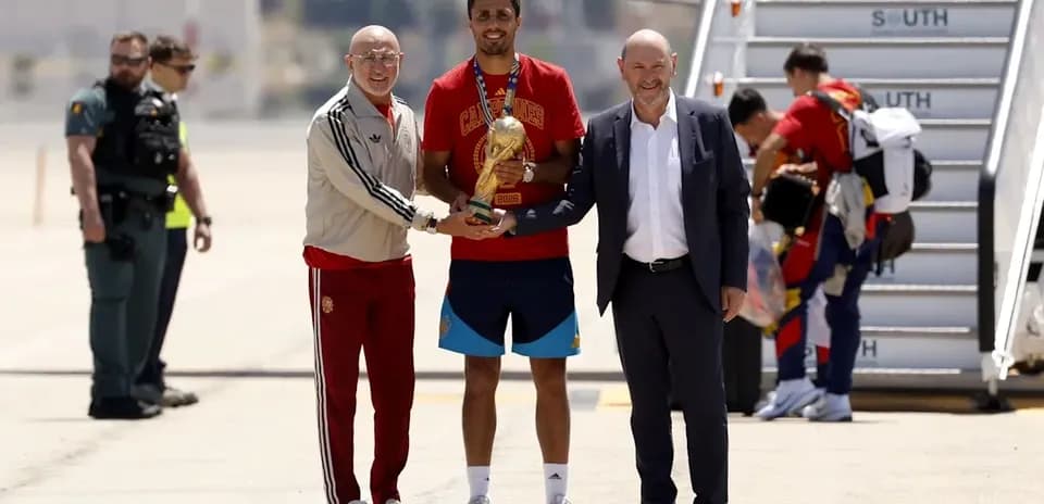 Jugadores y directivos celebrando con trofeo en aeropuerto