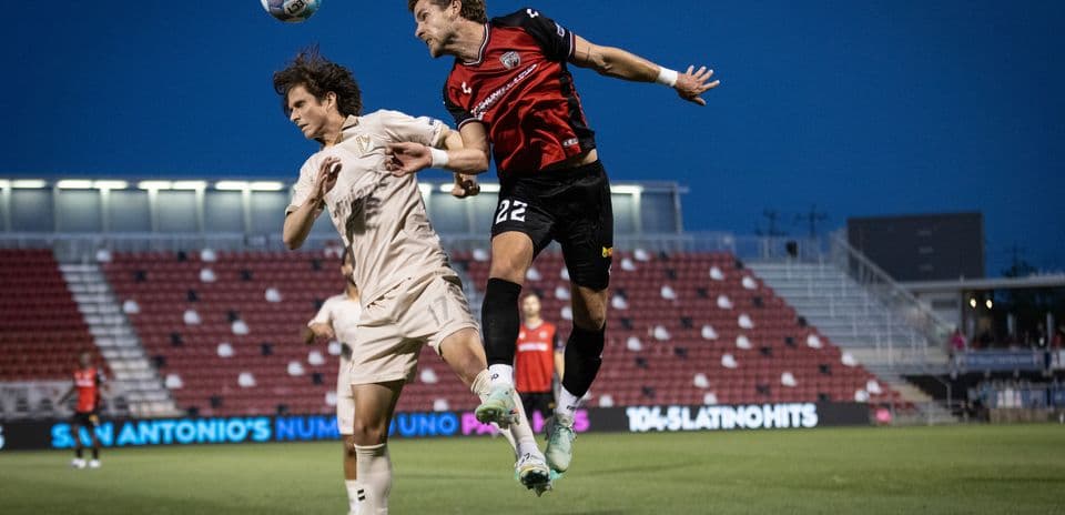 Jugador de FC Tulsa saltando por el balón