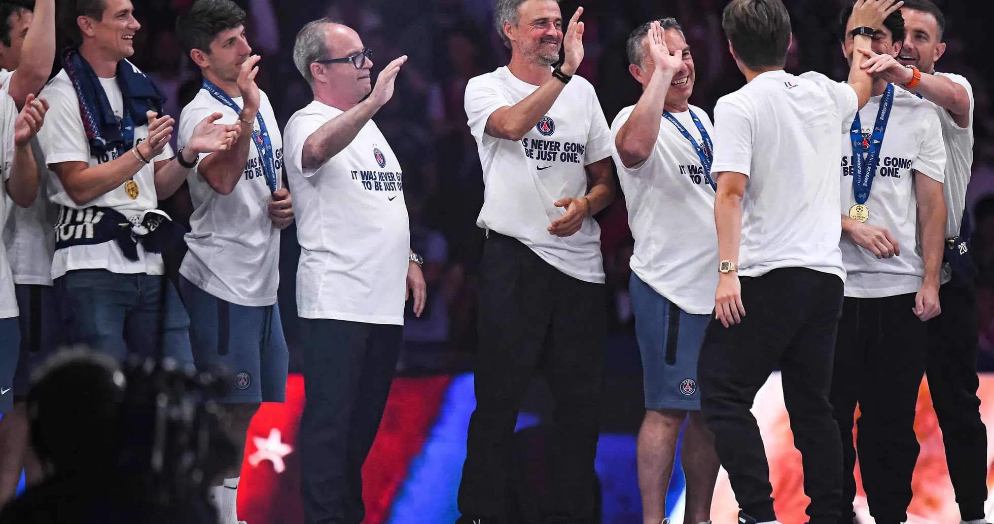 Equipo celebrando en el escenario con camisetas blancas