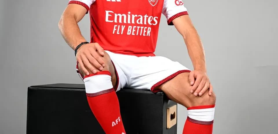 Jugador posando con uniforme de Arsenal y balón
