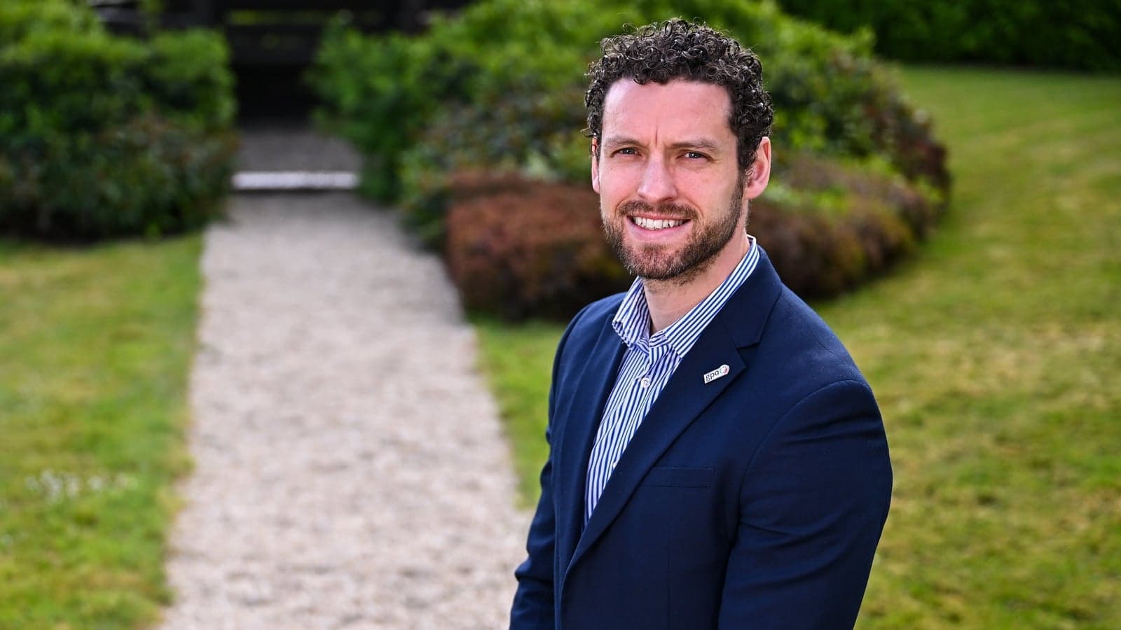 Persona sonriendo en un jardín con camino de grava