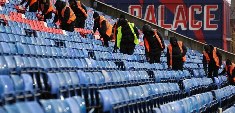 Trabajadores limpiando asientos en estadio de fútbol