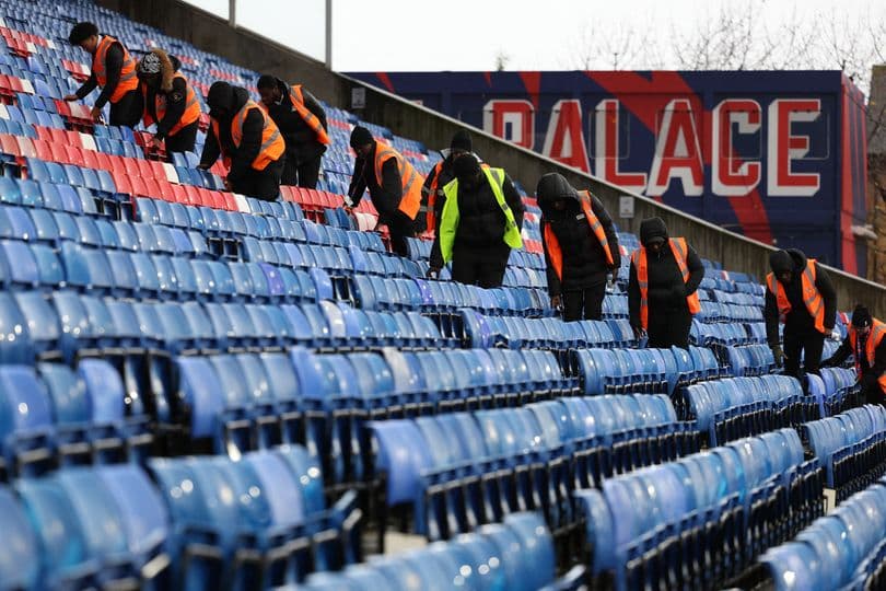 Trabajadores limpiando asientos en estadio de fútbol
