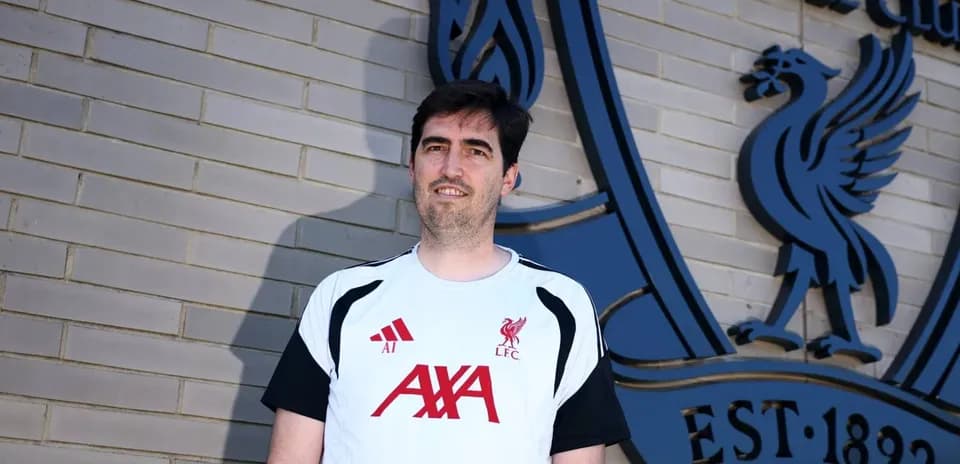 Entrenador posando frente al emblema del Liverpool