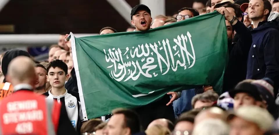 Afanáticos sosteniendo una bandera de Arabia Saudita en el estadio