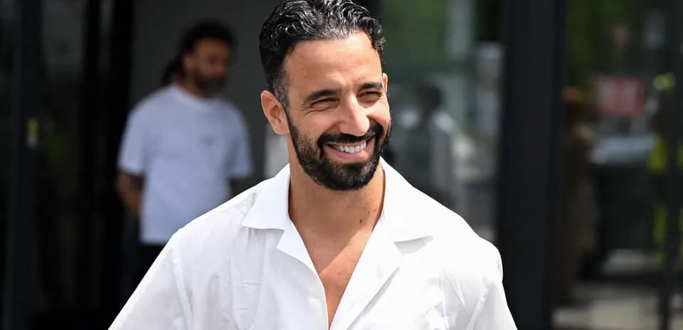 Hombre sonriente con camisa blanca saliendo de un edificio