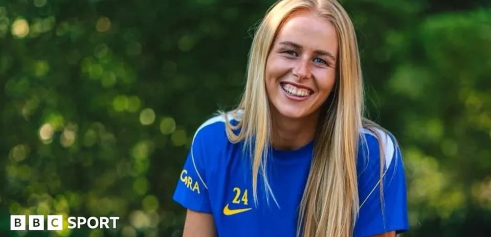 Jugadora de fútbol sonriendo con camiseta azul