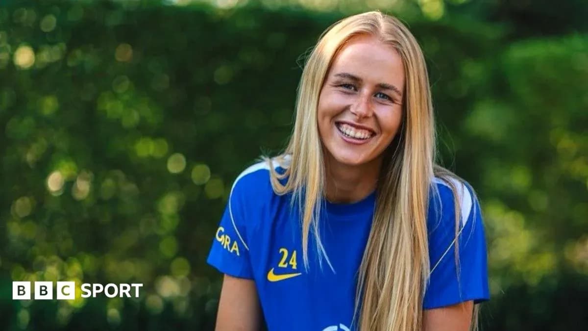 Jugadora de fútbol sonriendo con camiseta azul