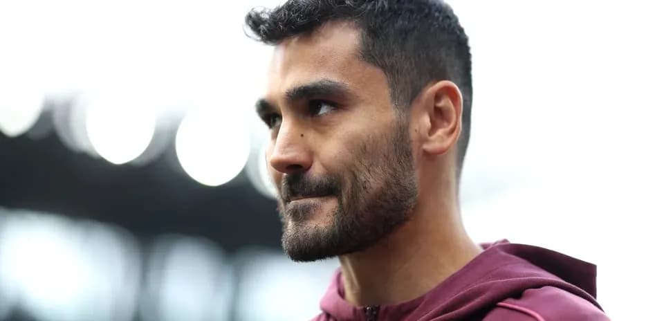 Jugador de fútbol con chaqueta morada en el campo