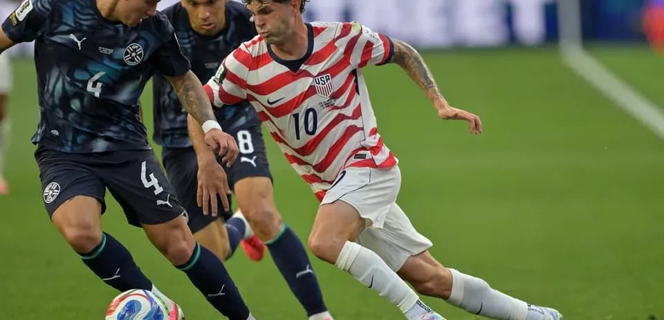 Christian Pulisic dribbling past Paraguay defenders