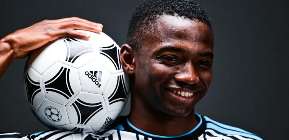 Jugador sosteniendo un balón de fútbol con una mano