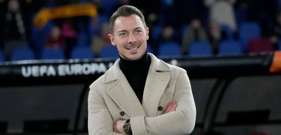 Hombre sonriendo con abrigo en estadio de fútbol