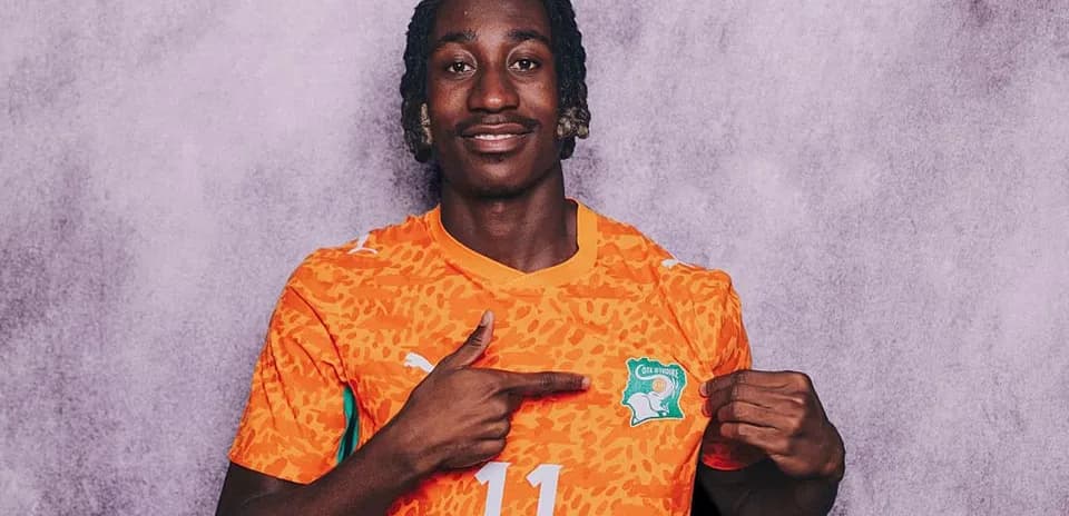 Jugador con camiseta naranja señalando el escudo de Côte d'Ivoire
