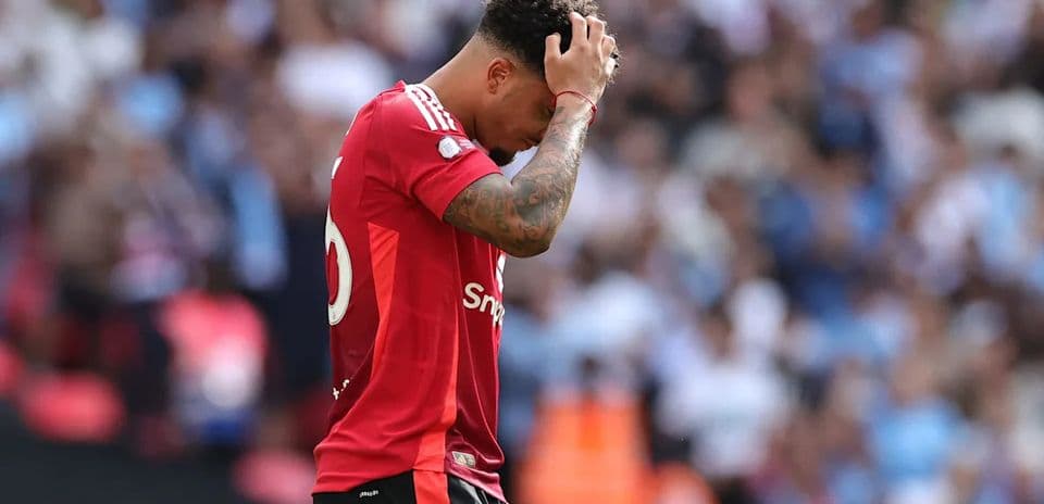 Jugador con camiseta roja se toma la cabeza en el campo