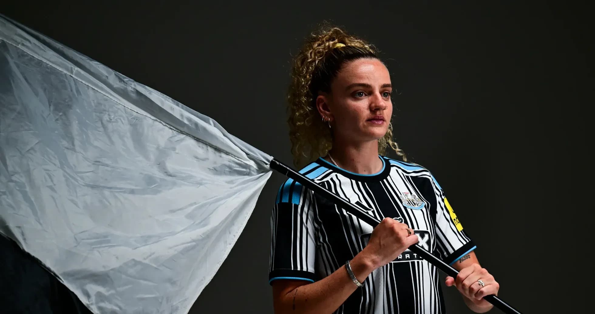 Jugadora sosteniendo una bandera en fondo oscuro