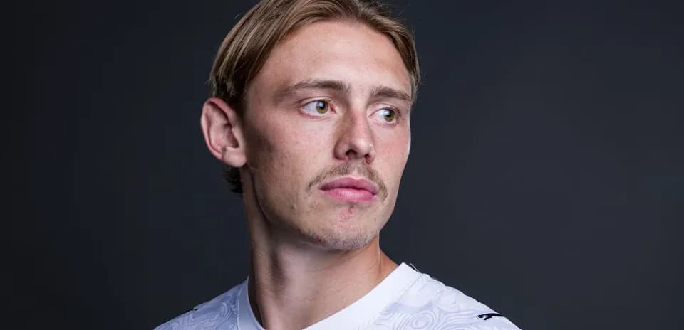 Jugador posando en camiseta blanca con fondo oscuro