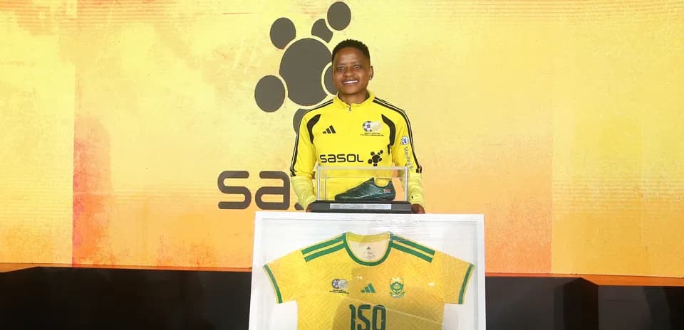Jugador sosteniendo una camiseta y botas en evento