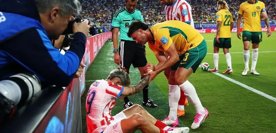 Jugador caído siendo asistido por oponente y árbitro