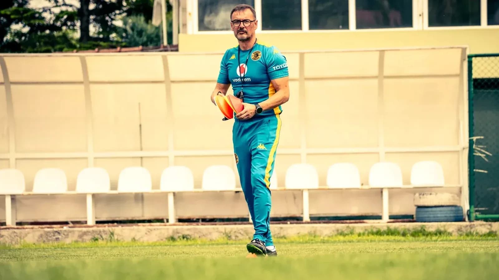 Entrenador caminando en el campo con conos