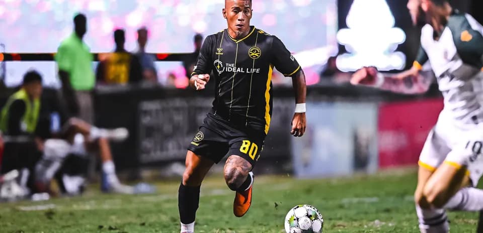 Jugador corriendo con el balón en el campo