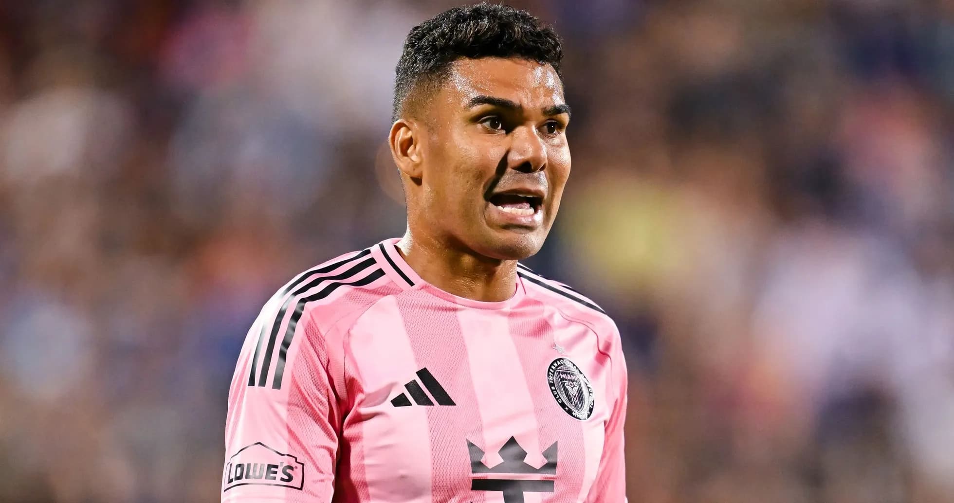 Jugador de fútbol en camiseta rosa hablando durante el partido