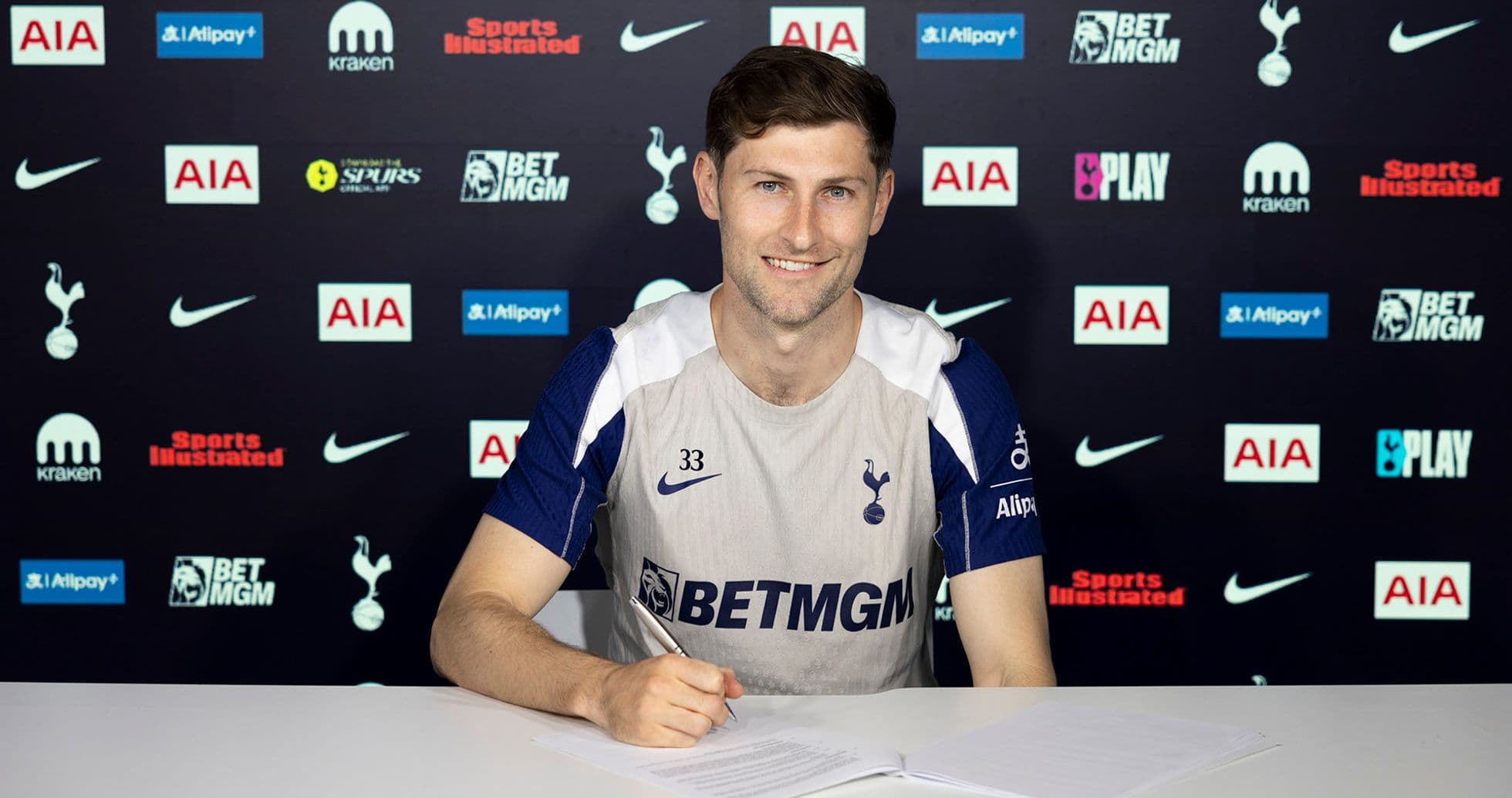 Jugador de Tottenham firmando contrato en mesa Jugador de Tottenham firmando contrato en mesa